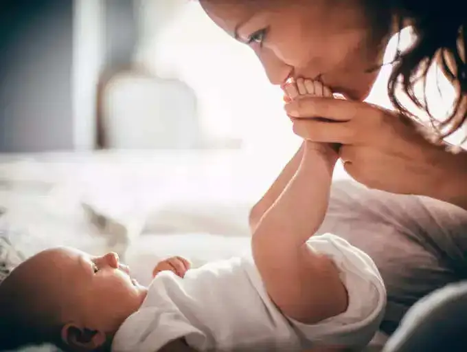 A mother kissing the feet of her newborn