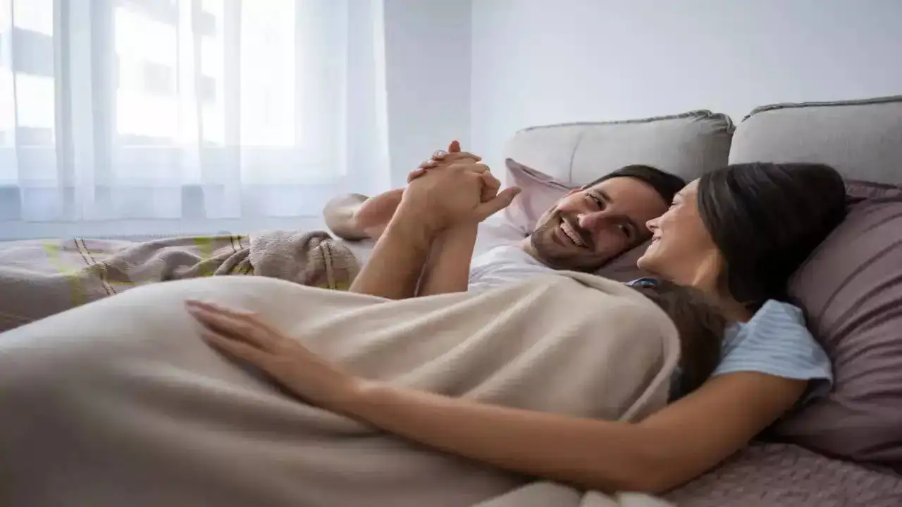 A man and woman in bed holding hands