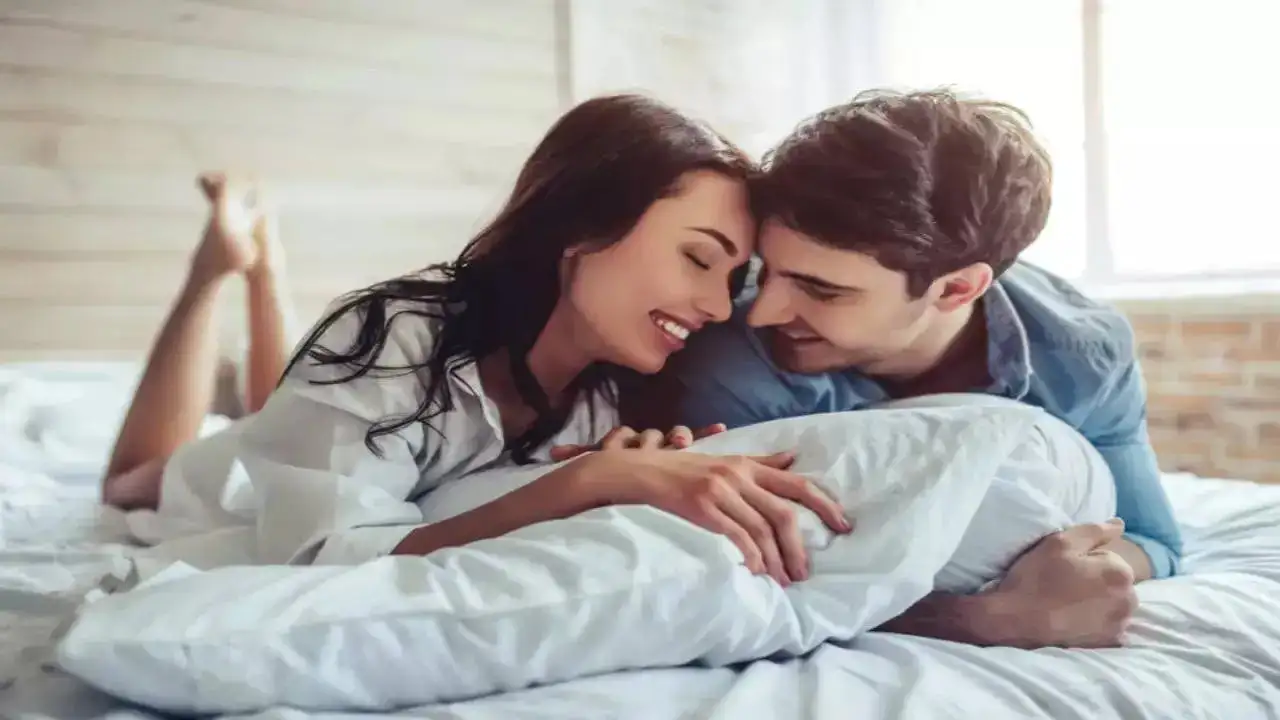 A man and woman smiling in bed