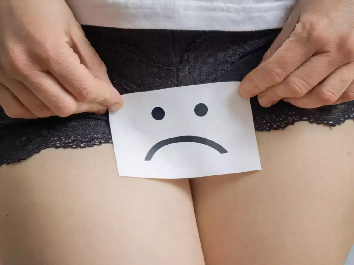 A woman holding a placard with a sad smiley face