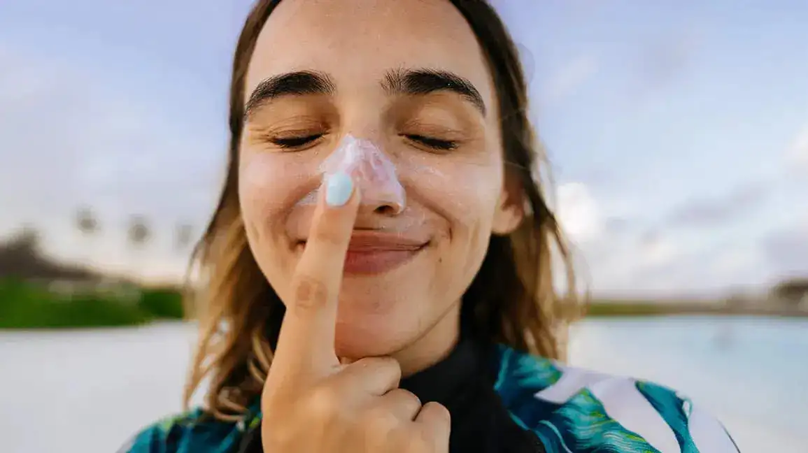 young-woman-eyes-closed-applying-sunscreen-sun-tan-lotion-on-face-1296x728-header.