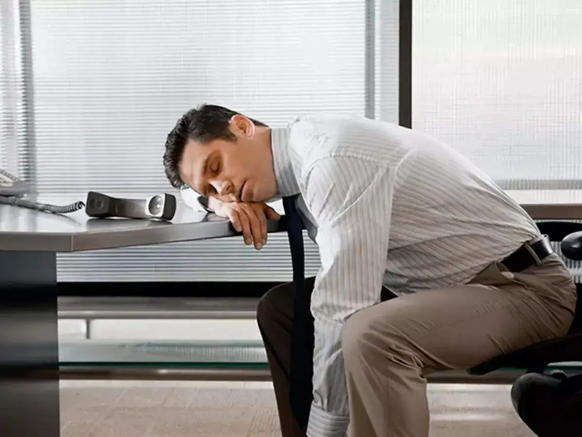 A man sitting on a chair with his head knelt down on a table